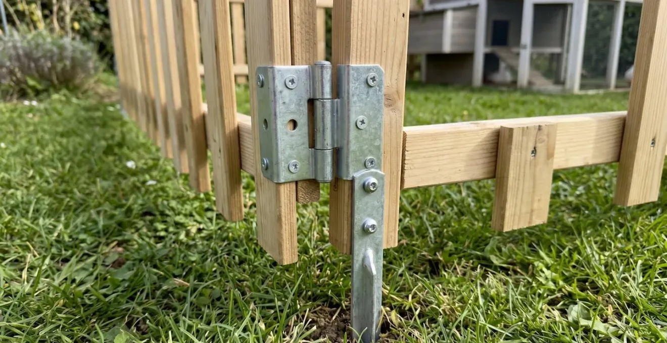 Gros plan sur un panneau de clôture mobile pour parcours de poules avec système de fixation modulaire enfoncé dans l'herbe